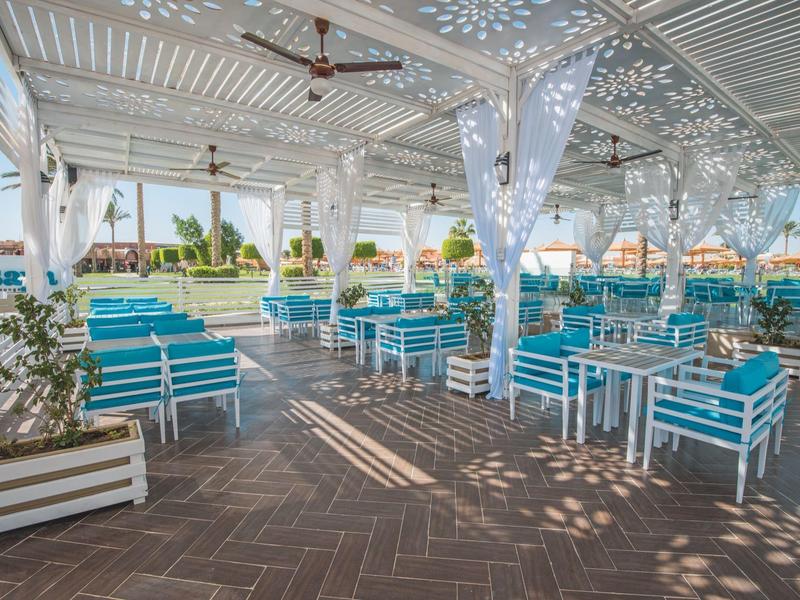 Zastřešená venkovní část s bílým a tyrkysovým posezením v hotelu.