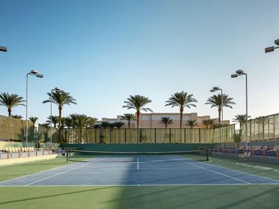 Pista de tenis al aire libre con palmeras y asientos bajo cielo despejado