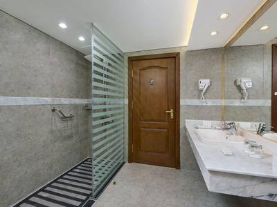 Moderní hotelová koupelna se sprchovým koutem bez vaničky, dřevěnými dveřmi a mramorovou umyvadlovou deskou.