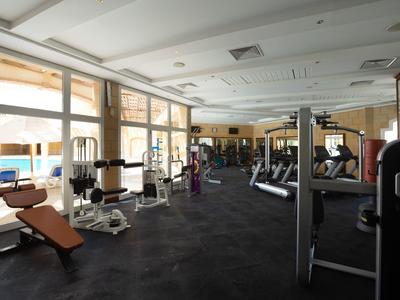 Gimnasio con equipo moderno y grandes ventanas con vista a la piscina.