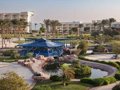 Hotel con bar en la piscina rodeado de vegetación y palmeras bajo un cielo despejado.