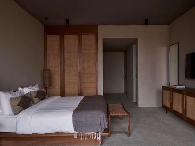 Modern eingerichtetes Hotelzimmer mit Bett, Holzschrank und Fernseher.