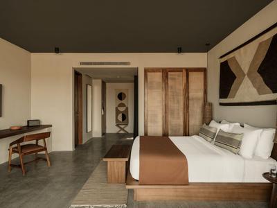 Modern hotel room with bed, desk, and abstract wall art.