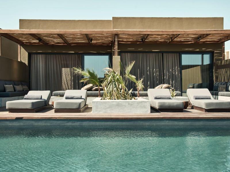 Moderner Außenbereich mit Pool, Sonnenliegen und schattiger Lounge im Hotel.