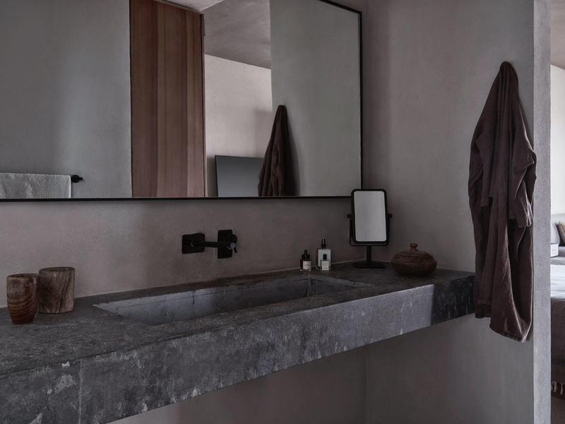 Moderner, grauer Waschtisch mit großem Spiegel und schwarzer Armatur in minimalistischem Bad.