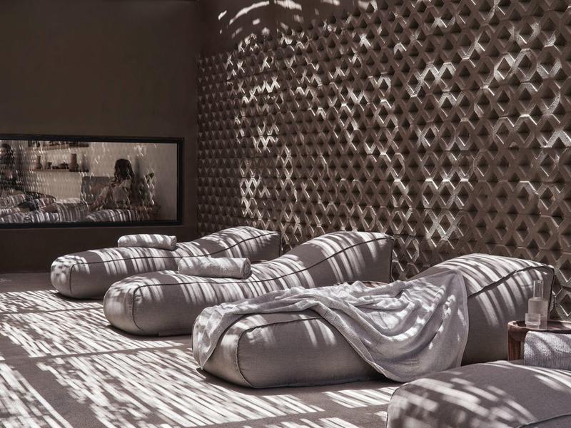 Gemütliche Lounge-Betten mit Decken und Schattenmuster an der Wand in ruhigem Raum.