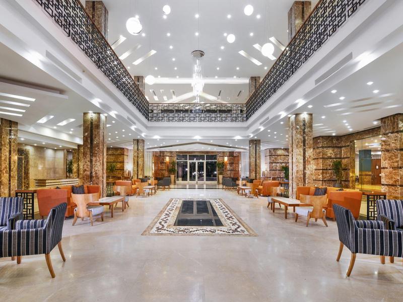 Große, elegante Hotellobby mit Marmorsäulen, modernen Sesseln und Deckengestaltung.