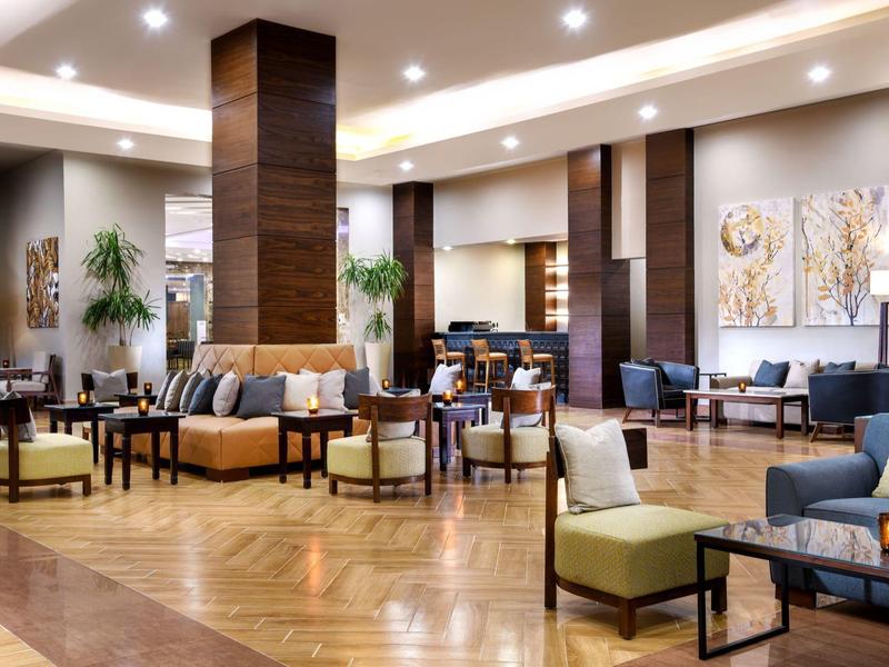 Großer, moderner Hotellobby mit bequemen Sesseln, Sofas und warmem Holzdesign.