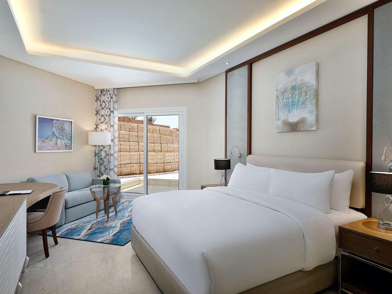 Helles Schlafzimmer mit großem Bett, Schreibtisch, modernen Lampen und Zugang zu Terrasse.