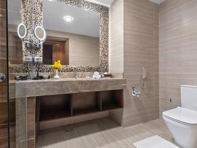Modernes Badezimmer mit großem Spiegel, Mosaikwand, grauem Waschtisch und weißer Toilette.