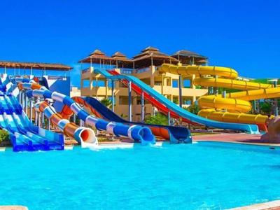Ein großer Wasserpark mit bunten Wasserrutschen und klarem blauem Pool unter strahlend blauen Himmel.