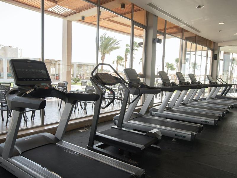 Gym with multiple treadmills next to large windows overlooking outside.