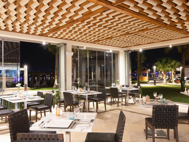 Empty sandy beach with wooden sun umbrellas and a yellow boat by calm sea