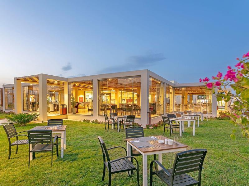 Modern hotel area with outdoor seating and a garden at sunset.