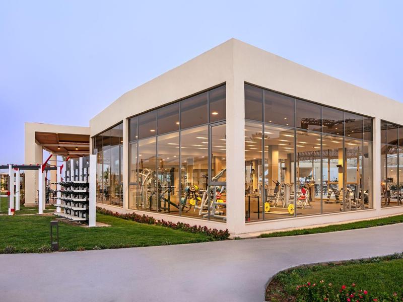 Modern building with large glass windows and wooden accents in a green setting.