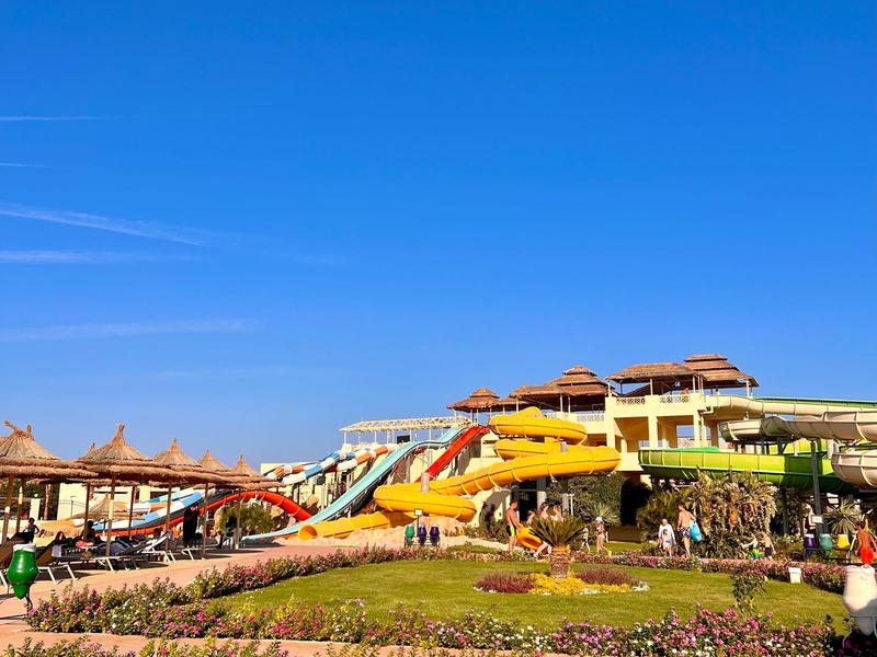 Colorful water slides and landscaped lawns under a clear blue sky in a water park.