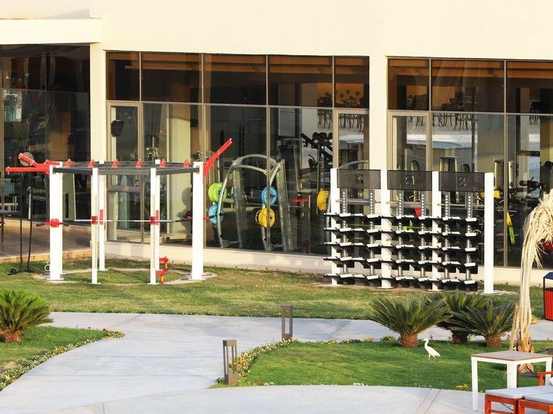 Modern outdoor area with fitness equipment in front of a building's glass facade.