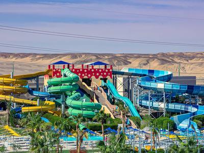 Bunte Wasserrutschen in einem Wasserpark vor einer Wüstenlandschaft