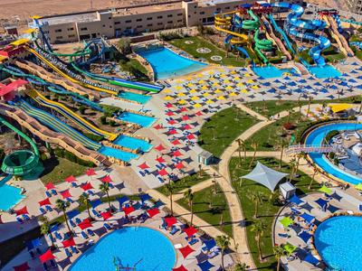 Een druk waterpark met meerdere glijbanen, zwembaden en kleurrijke parasols op een zonnige dag.