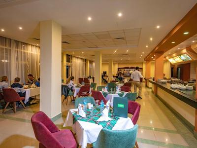 Ein gut beleuchteter Hotelrestaurantbereich mit gedeckten Tischen und Gästen.