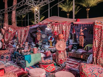 Orientalischer Marktstand mit Teppichen, Kissen und traditionellen Handwerkswaren bei Nacht.