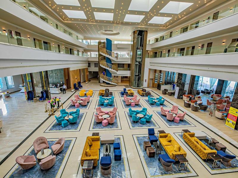 Großer heller Raum mit moderner Einrichtung, bunten Sofas und Tischen in symmetrischer Anordnung.