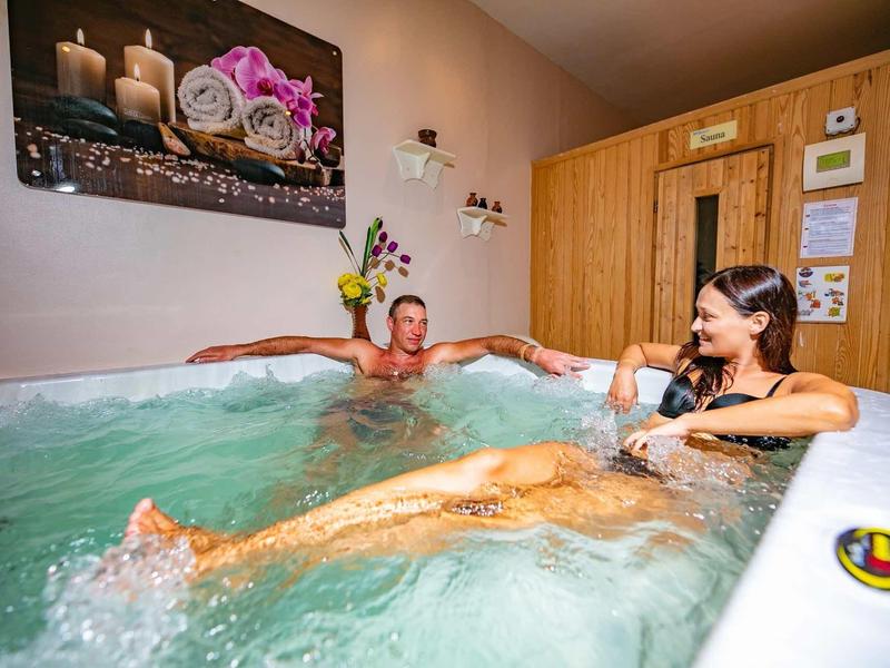 Zwei Frauen entspannen in einem Whirlpool in einem hellen, gemütlichen Holzzimmer.