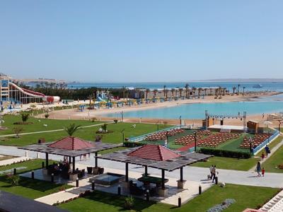 Parque acuático grande con toboganes, un lago y céspedes verdes bajo un cielo azul claro.