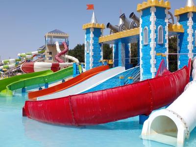 Parque acuático colorido con toboganes y piscina bajo un cielo despejado.