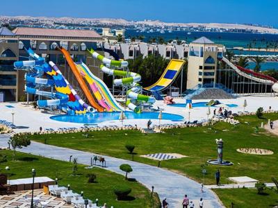 Gran parque acuático con toboganes coloridos y piscinas cerca de un hotel junto al mar.
