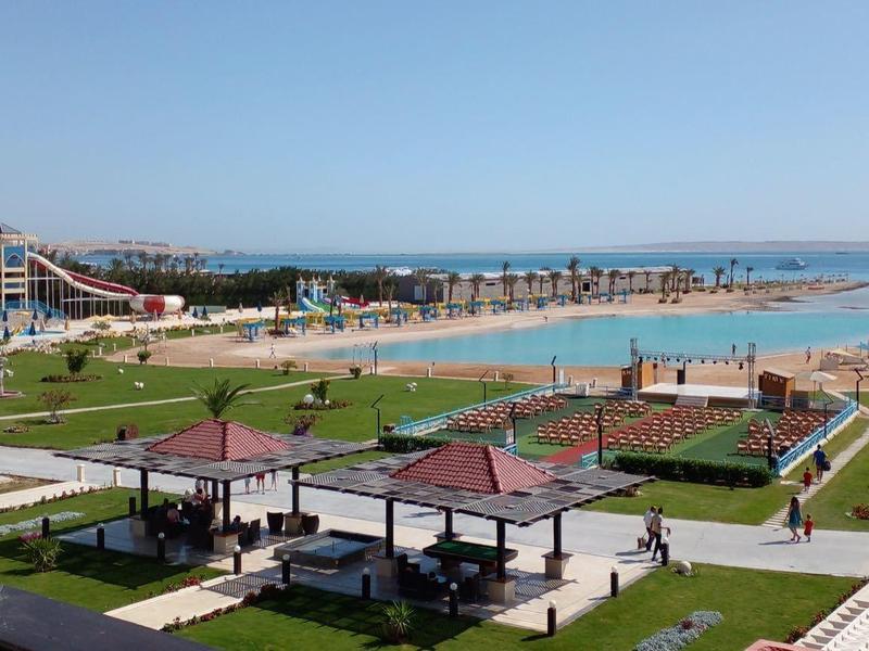 Amusement park and beach with clear sky, green areas, and seating near the coast.