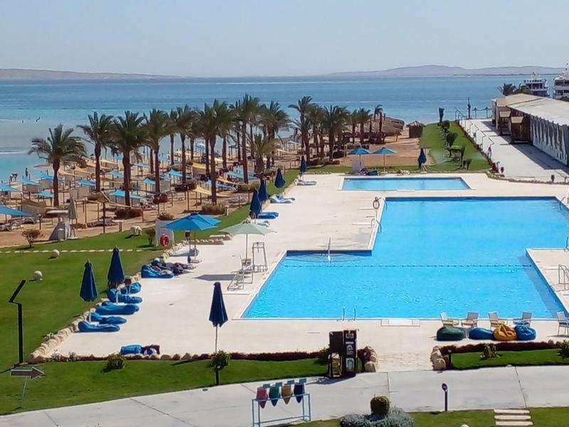 Large outdoor pool with sun loungers and sea view at a hotel resort.