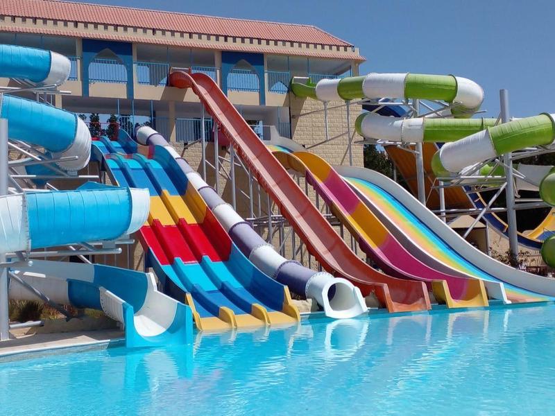 Several colorful water slides lead into a large pool at a holiday resort.