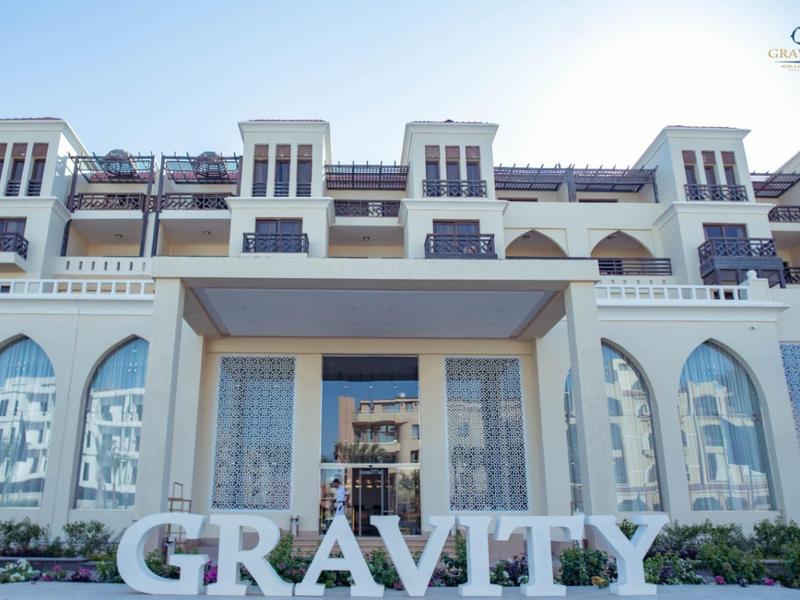 Modern multi-story hotel building with large windows and 'GRAVITY' sign in front.