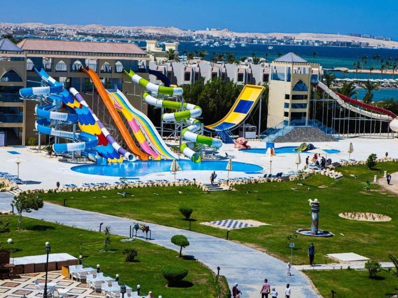 A large water park with colorful slides and a pool at a hotel resort by the sea.