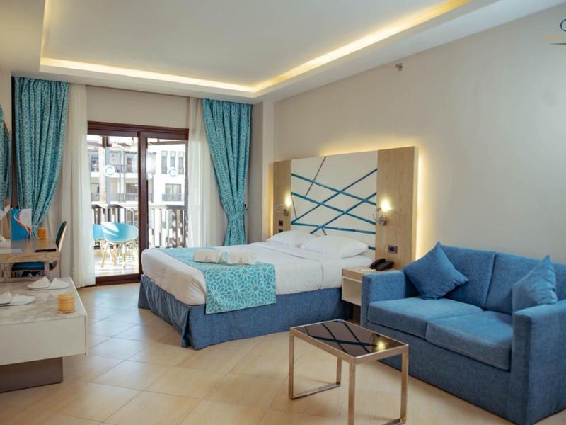 Modern hotel room with double bed, sofa, and balcony.