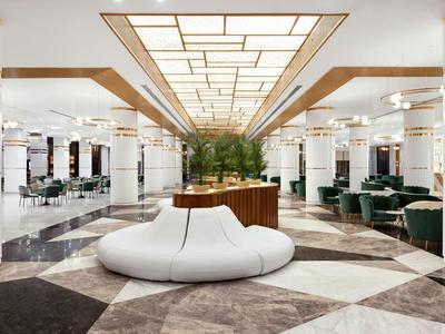 Lobby de hotel luminosa con diseño moderno del techo y sofá blanco redondo en el centro.