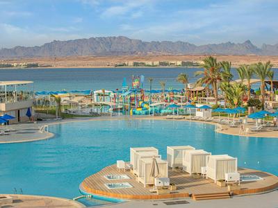 Gran piscina de hotel con tumbonas, toboganes de agua y vistas a montañas y mar