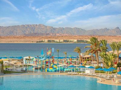 Uitzicht vanaf het zwembad op waterpark en bergen met heldere blauwe lucht.