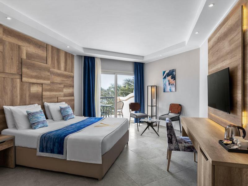 Ruime hotelkamer met tweepersoonsbed, houten accenten en een balkon met zitje buiten.