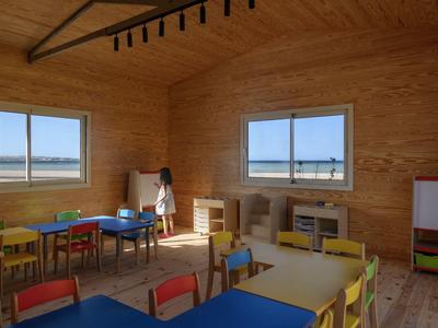 Kindergartenraum mit bunten Tischen und Stühlen, hellen Holzwänden und Fenster mit Blick nach draußen.
