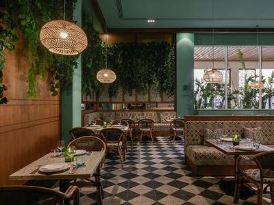 Accogliente area ristorante con luci sospese, piante verdi e pavimento a scacchiera.