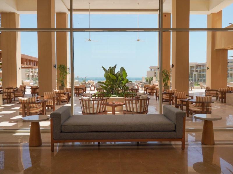 Salon d'hôtel lumineux avec de grandes fenêtres et vue sur la ville