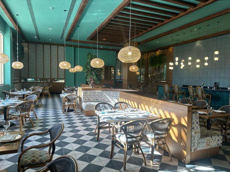 Restaurant élégant avec sol en carreaux noirs et blancs, mobilier moderne et luminaires suspendus.