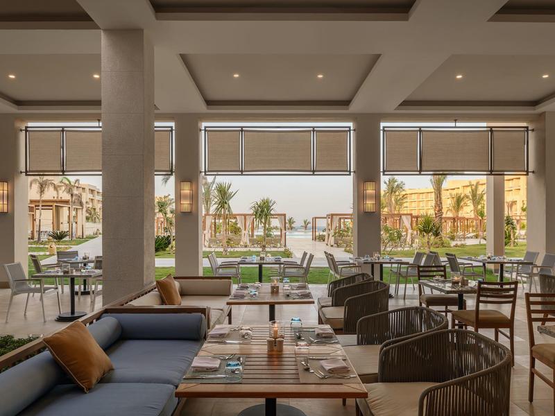 Restaurant d'hôtel moderne avec espaces assis et vue sur jardin avec piscine