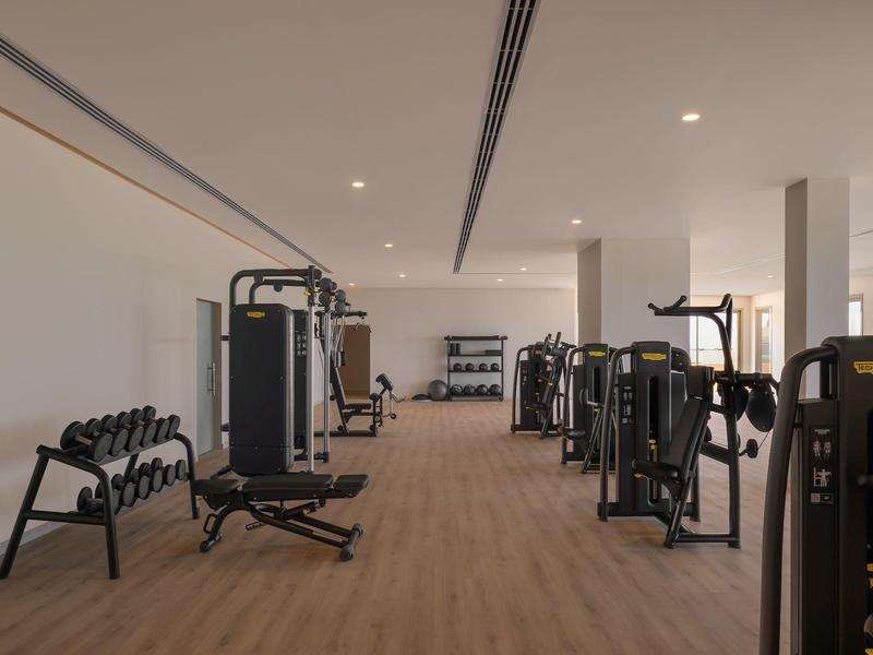 Grande salle de sport avec équipements modernes et haltères sur sol en bois