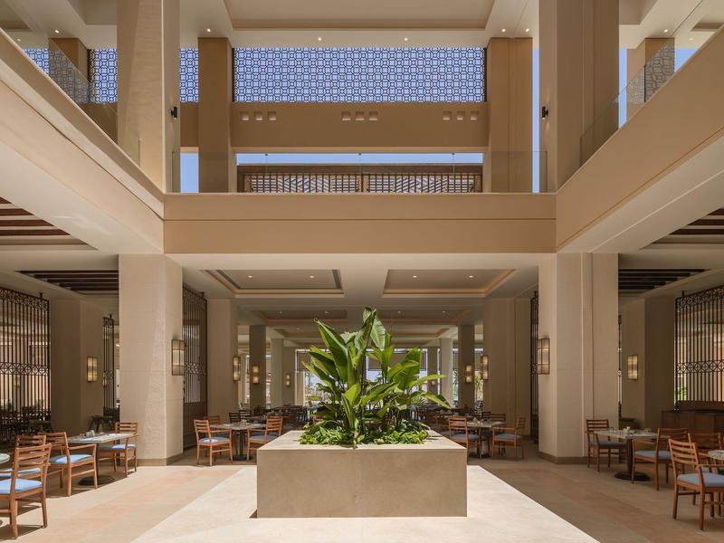 Hall d'hôtel spacieux avec plantes centrales et plusieurs espaces assis