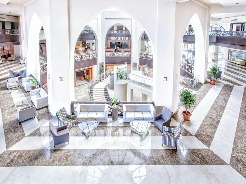 Helle und großzügige Empfangshalle mit weißen Säulen und modernen Sitzgruppen.