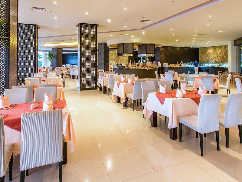 Helles Restaurant mit weißen Stühlen, gedeckten Tischen und warmem Deckenlicht.