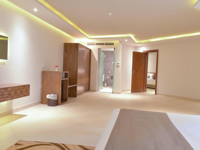 Großes, modern eingerichtetes Zimmer mit indirekter Beleuchtung, Holzmöbeln und hellen Wänden.